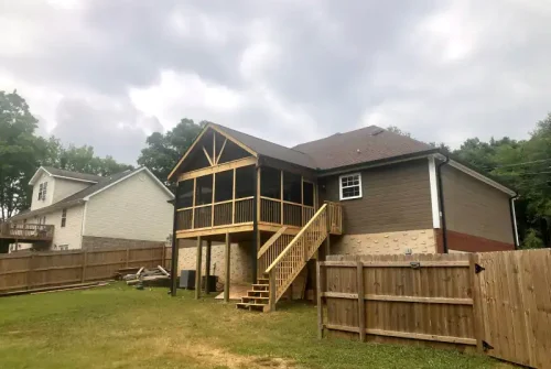 A deck under construction on the back of a house with stairs leading up to the upper level.